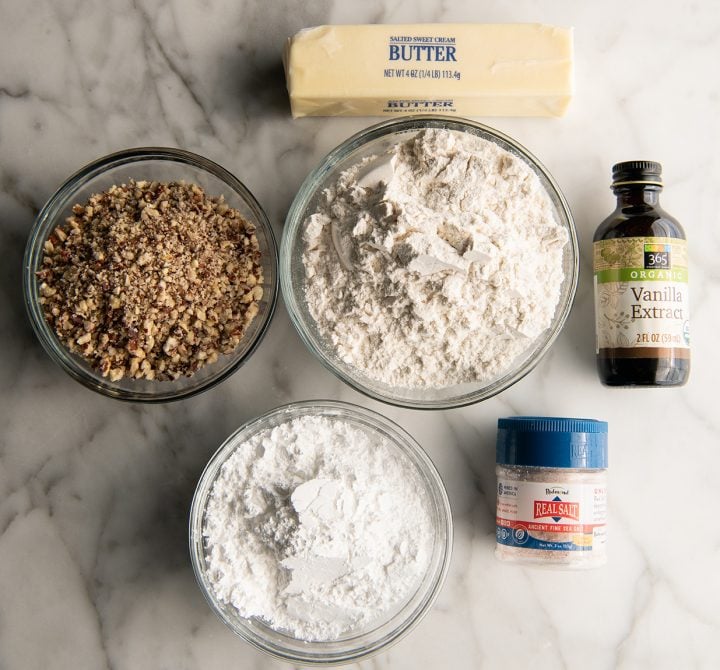Pecan Snowball Cookies are easy to make with 7 ingredients. They are buttery, nutty, and melt-in your mouth delicious. These butterball cookies are an old family recipe, and a must-make Christmas cookie! overhead view of the ingredients in this snowball cookie recipe