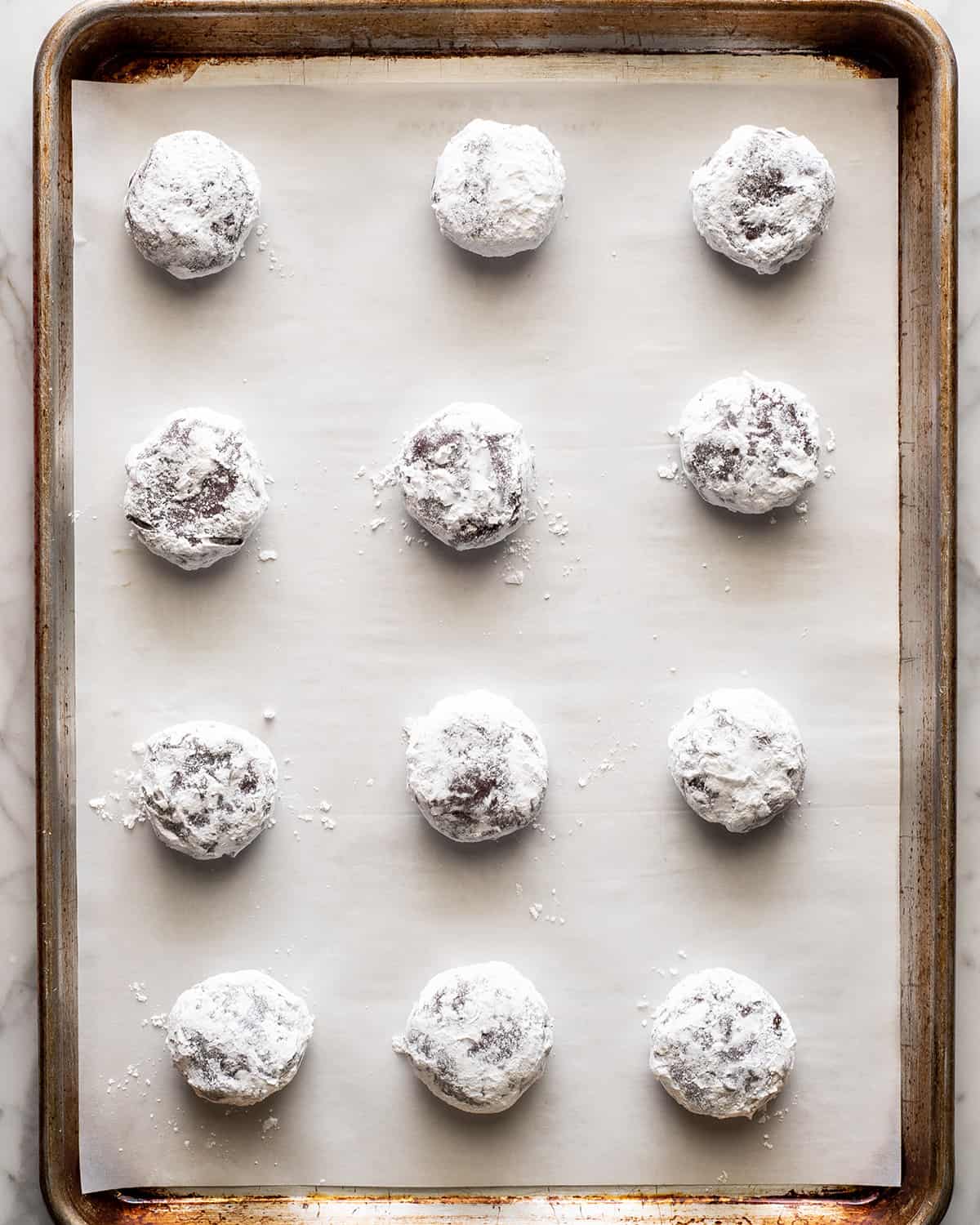 crinkles coated in powdered sugar on a baking sheet before baking