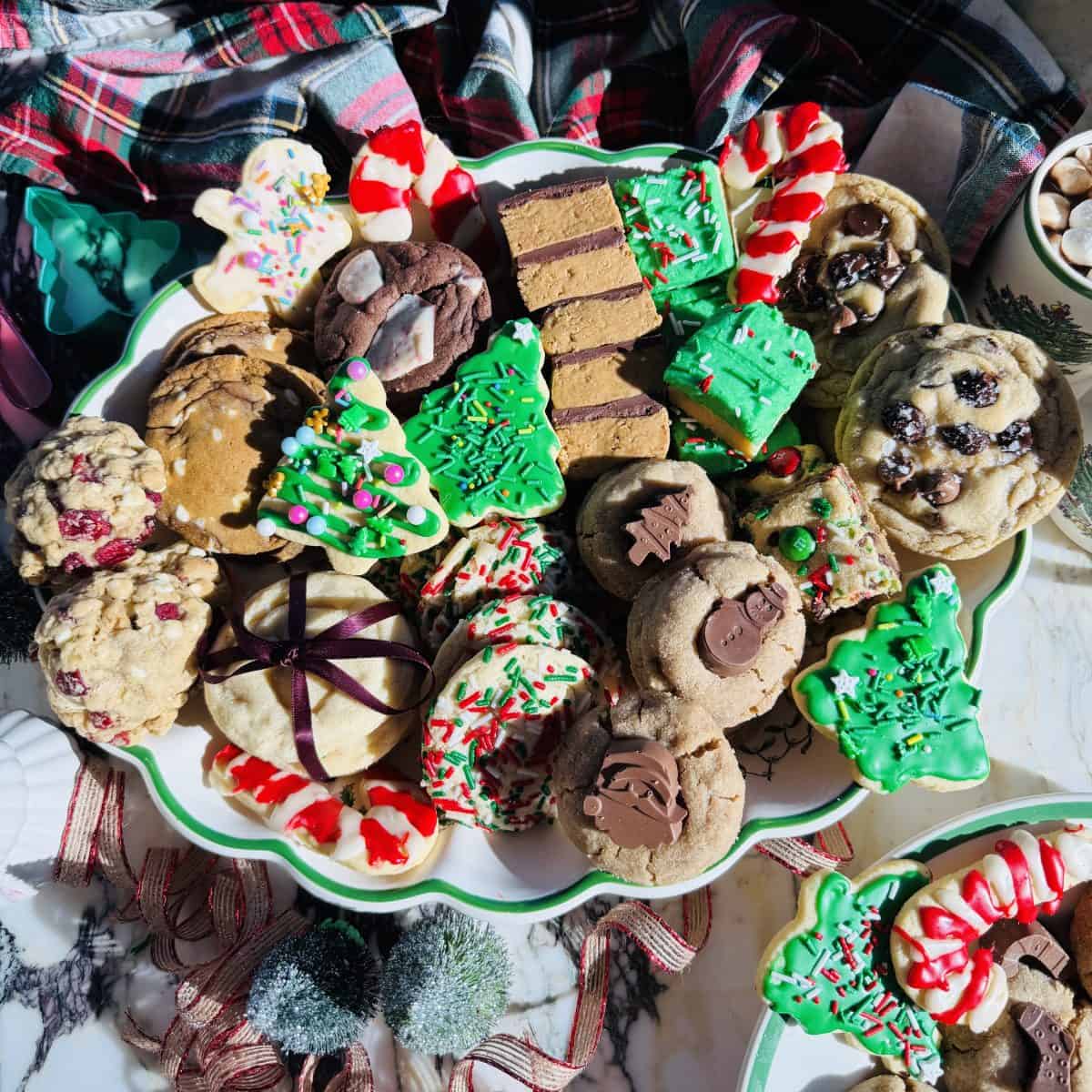 a tray of Christmas cookies including cut out sugar cookies, peanut butter blossoms, oatmeal cranberry cookies, chocolate chip cookies and more. 