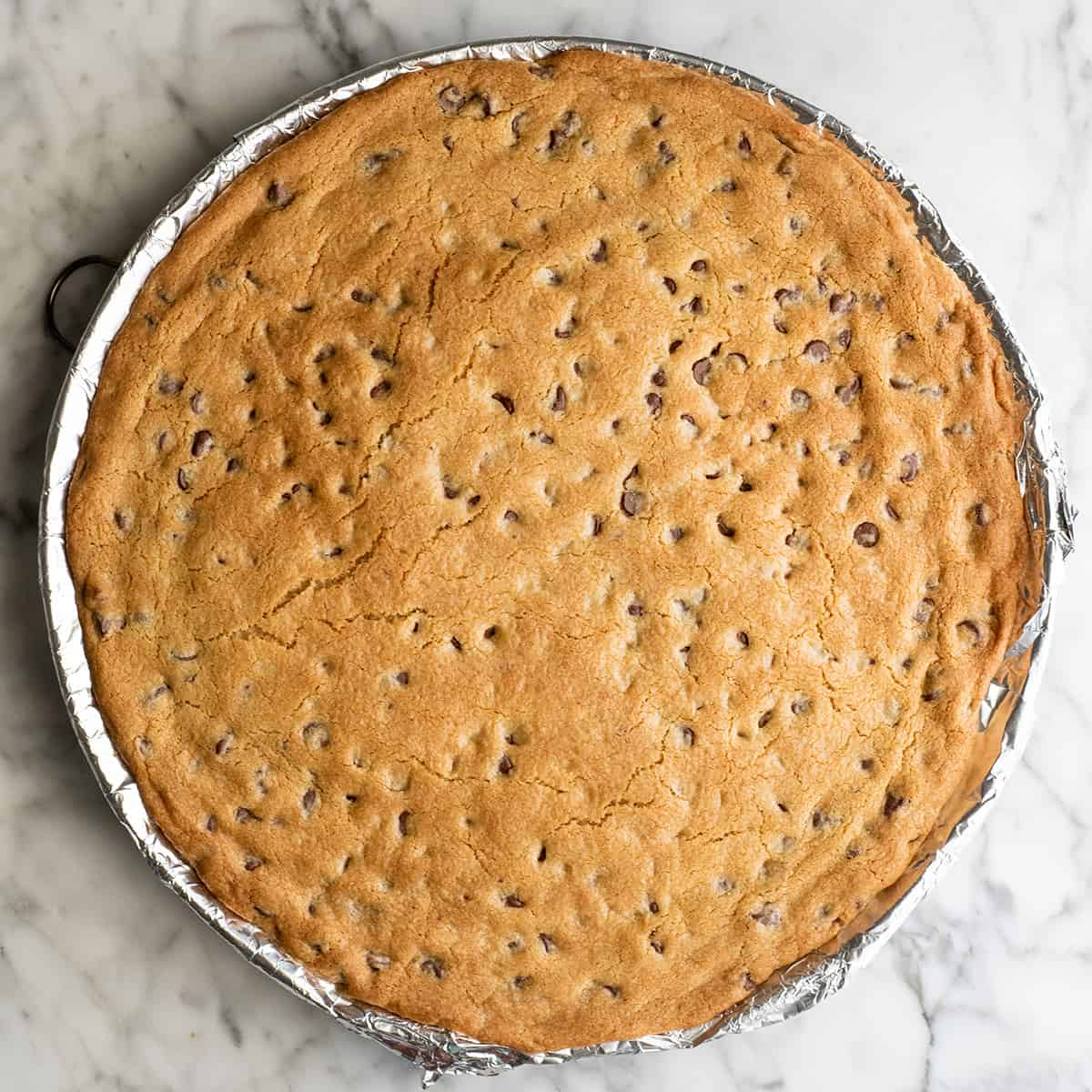 chocolate chip cookie cake on a baking sheet after baking