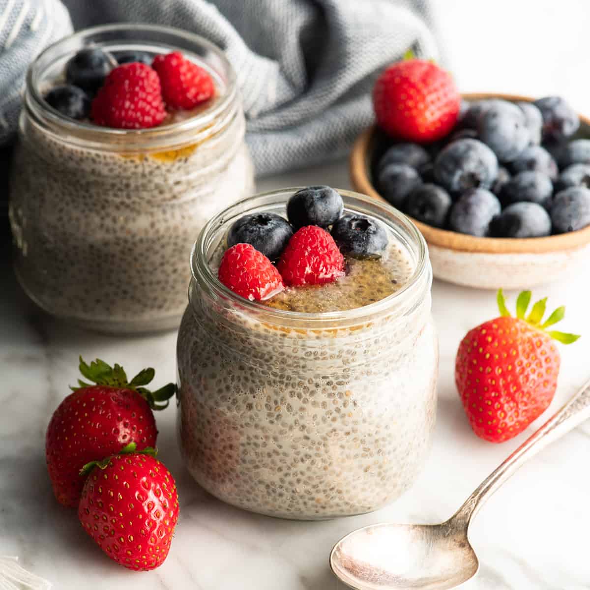 two jars of healthy chia pudding with berries and honey on top