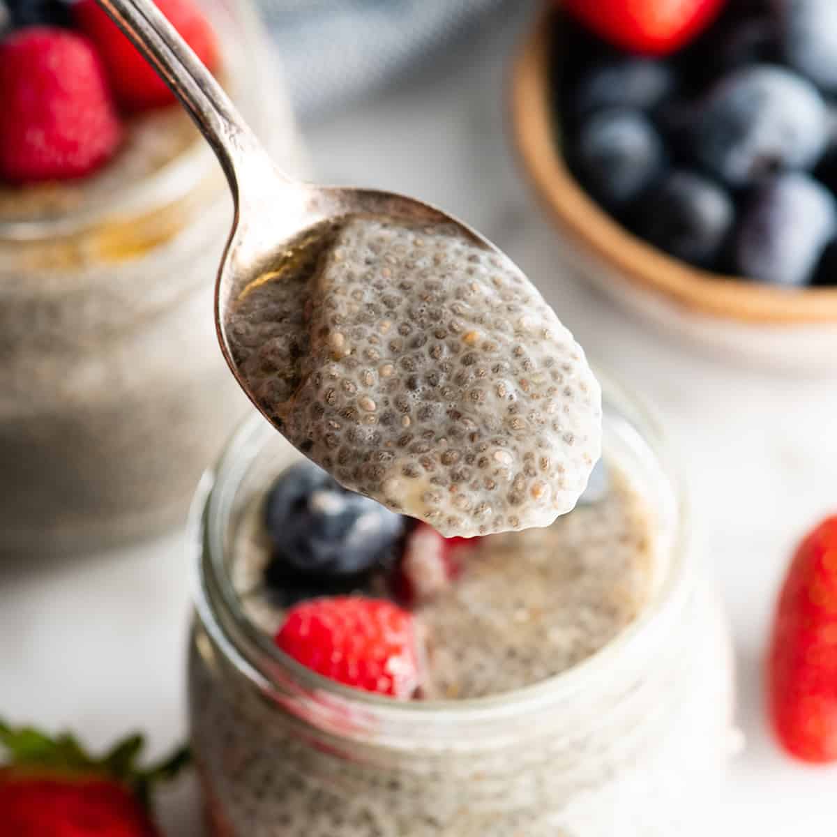 a soon taking a scoop of chia pudding from a jar 