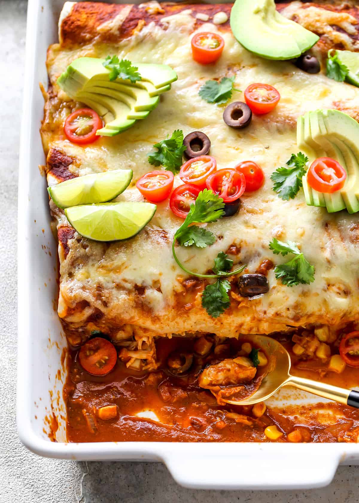 overhead view of Chicken Enchiladas in a baking dish with a serving spoon