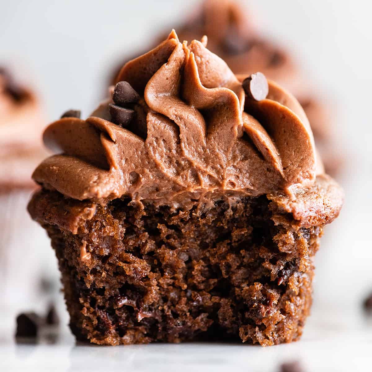 up close front view of a chocolate cupcake cut in half with chocolate frosting