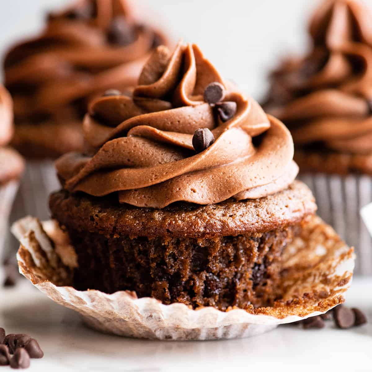 front view of a chocolate cupcake with chocolate frosting with the wrapper unwrapped