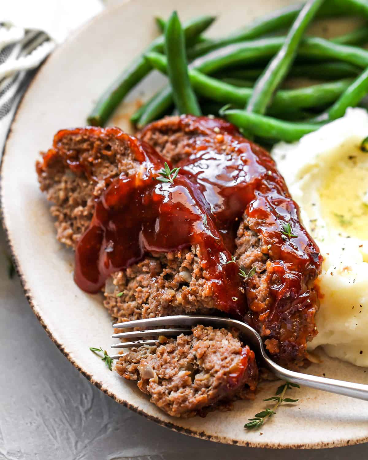 two slices of meatloaf on a plate with a fork taking a bite