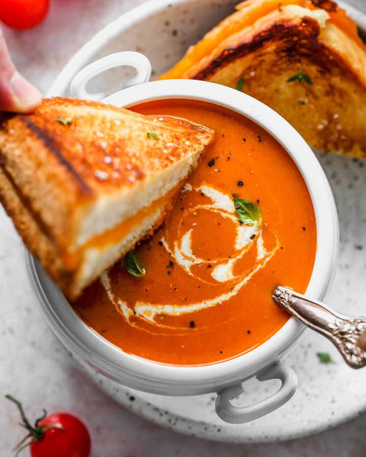 overhead photo of grilled cheese being dipped into a bowl of Homemade Tomato Soup