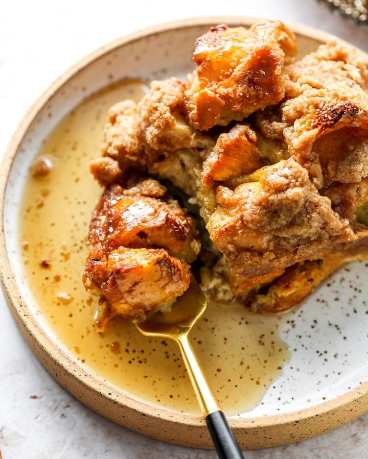 The best Baked French Toast Casserole recipe is an easy & delicious breakfast. French bread is combined with a sweet vanilla egg & milk mixture and topped with a buttery streusel topping. This overnight French toast casserole is made at night and baked in the morning so it's easy to prepare and enjoy! a piece of Baked French Toast Casserole on a plate with syrup