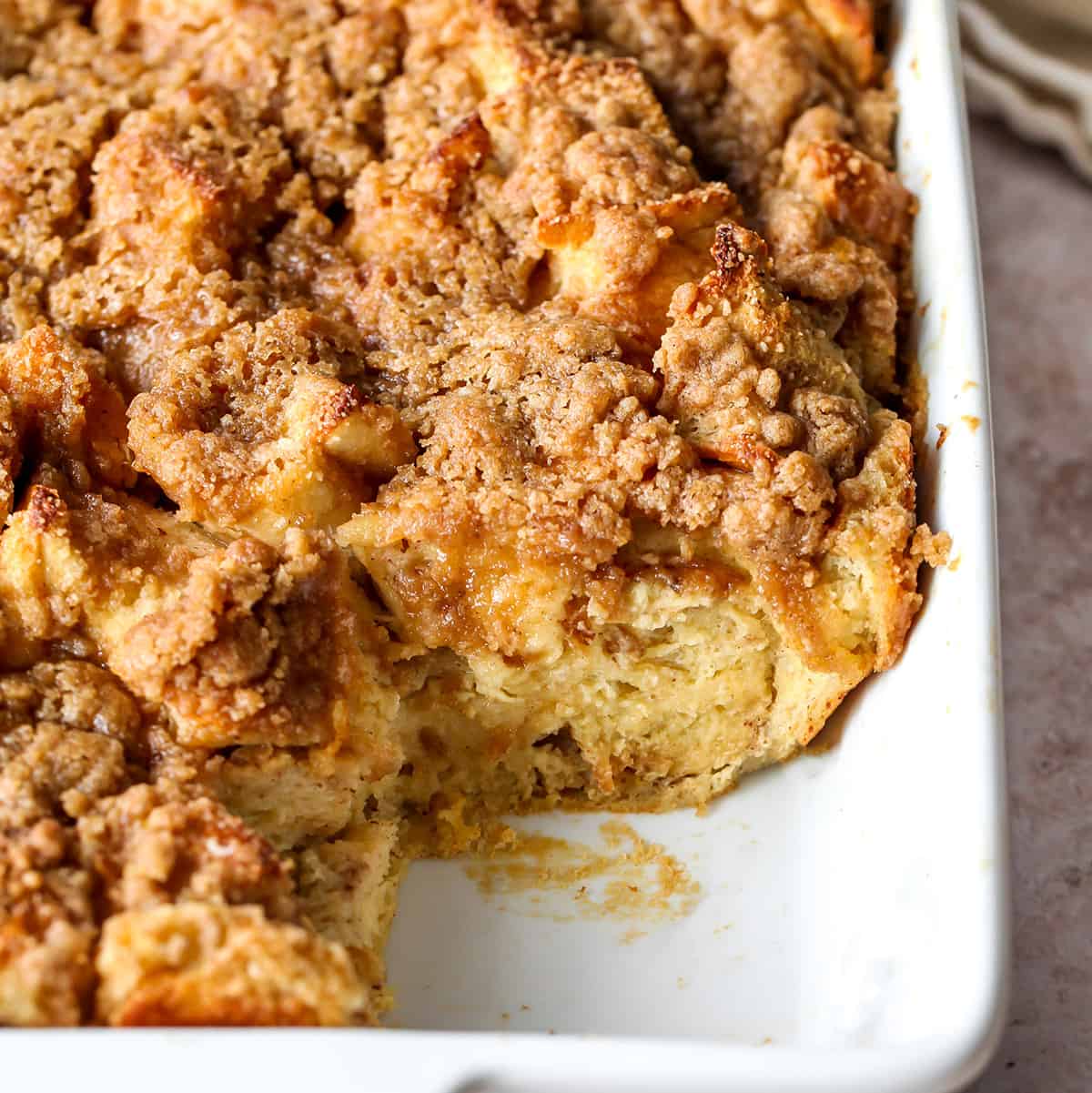 overnight french toast casserole in a baking dish with a piece cut out of it