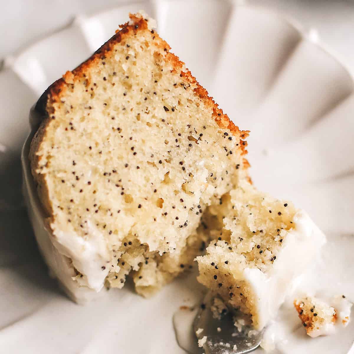 a fork taking a bite of Poppy Seed Cake  on a plate
