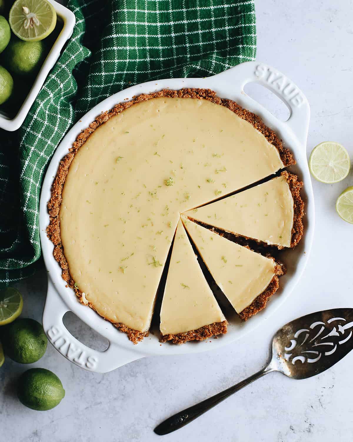 overhead photo fo a key lime pie with 3 slices cut in a pie dish