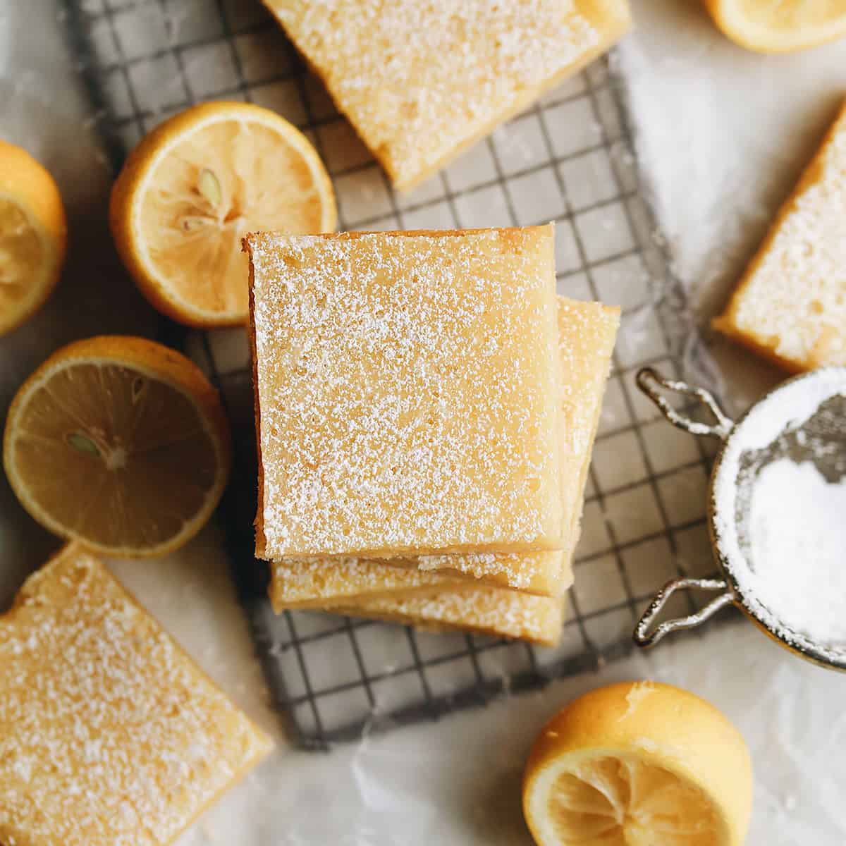 overhead view of a stack of lemon bars with lemons and other bars around it