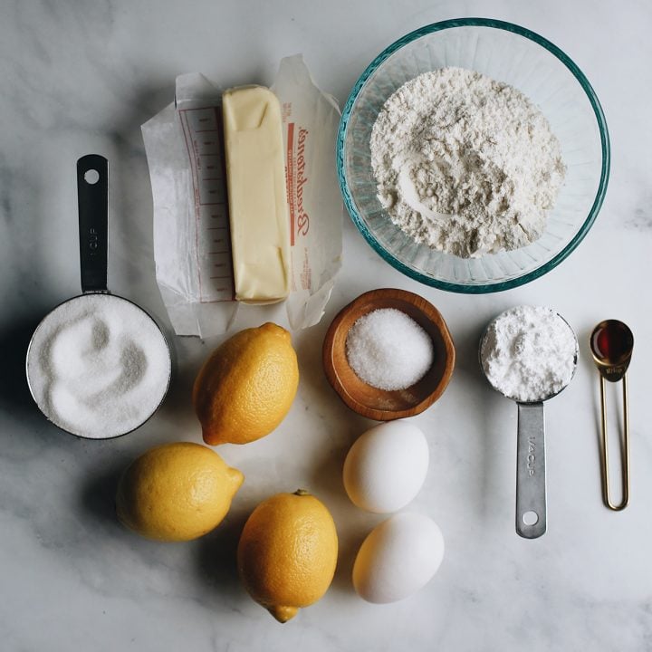 The best lemon bars! A smooth & sweet lemon filling sits on top of a buttery shortbread crust for the most delicious lemon squares recipe. Plus these easy lemon bars are simple to make with only 8 ingredients! overhead photo of the ingredients in this Lemon Bars Recipe