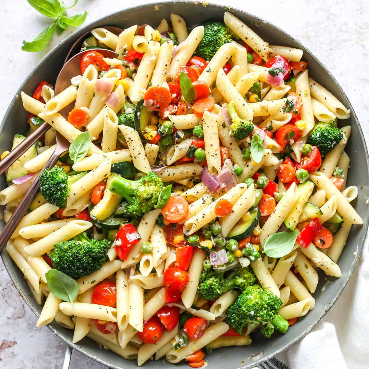 photo of pasta primavera in a pan with serving spoons