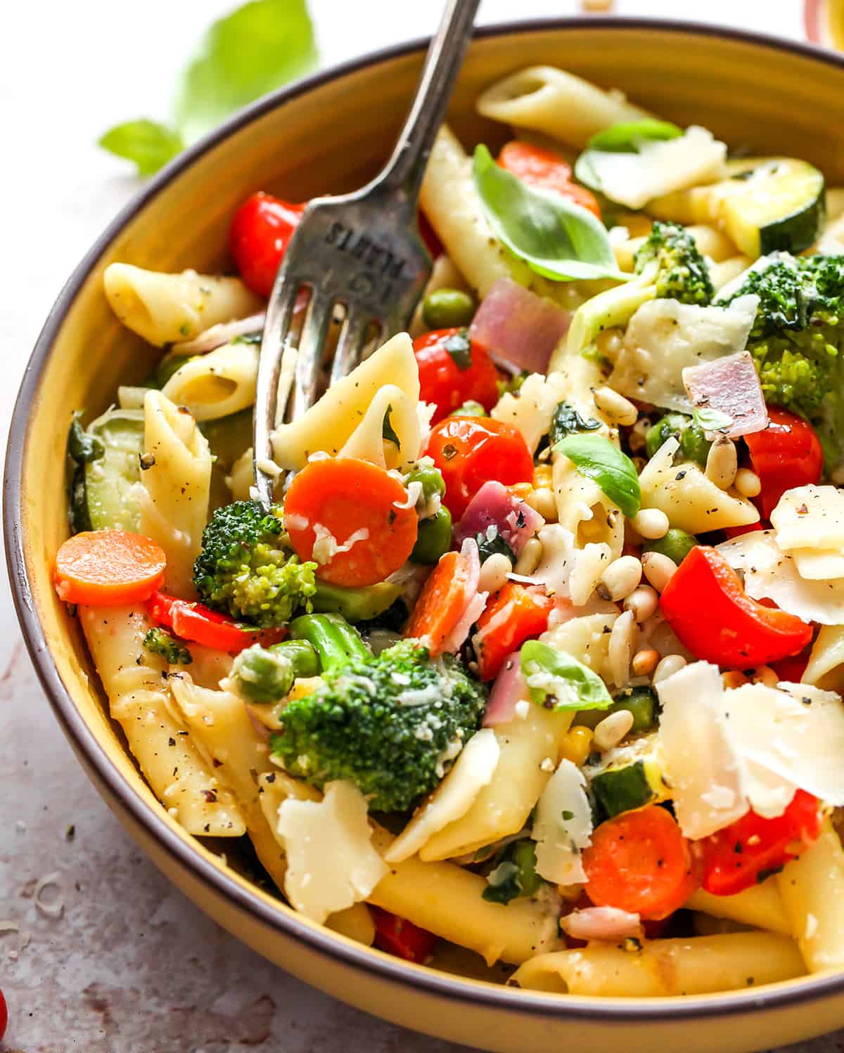 pasta primavera in a bowl with a fork taking a bite
