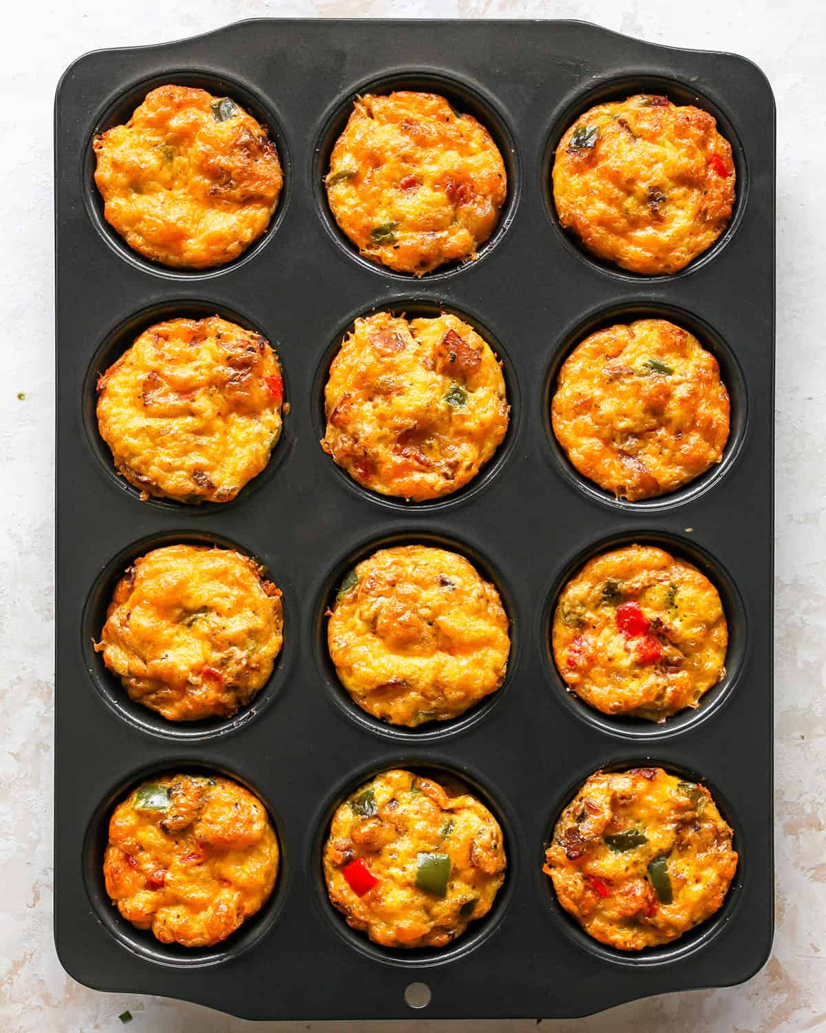 12 egg bites in a muffin pan after baking