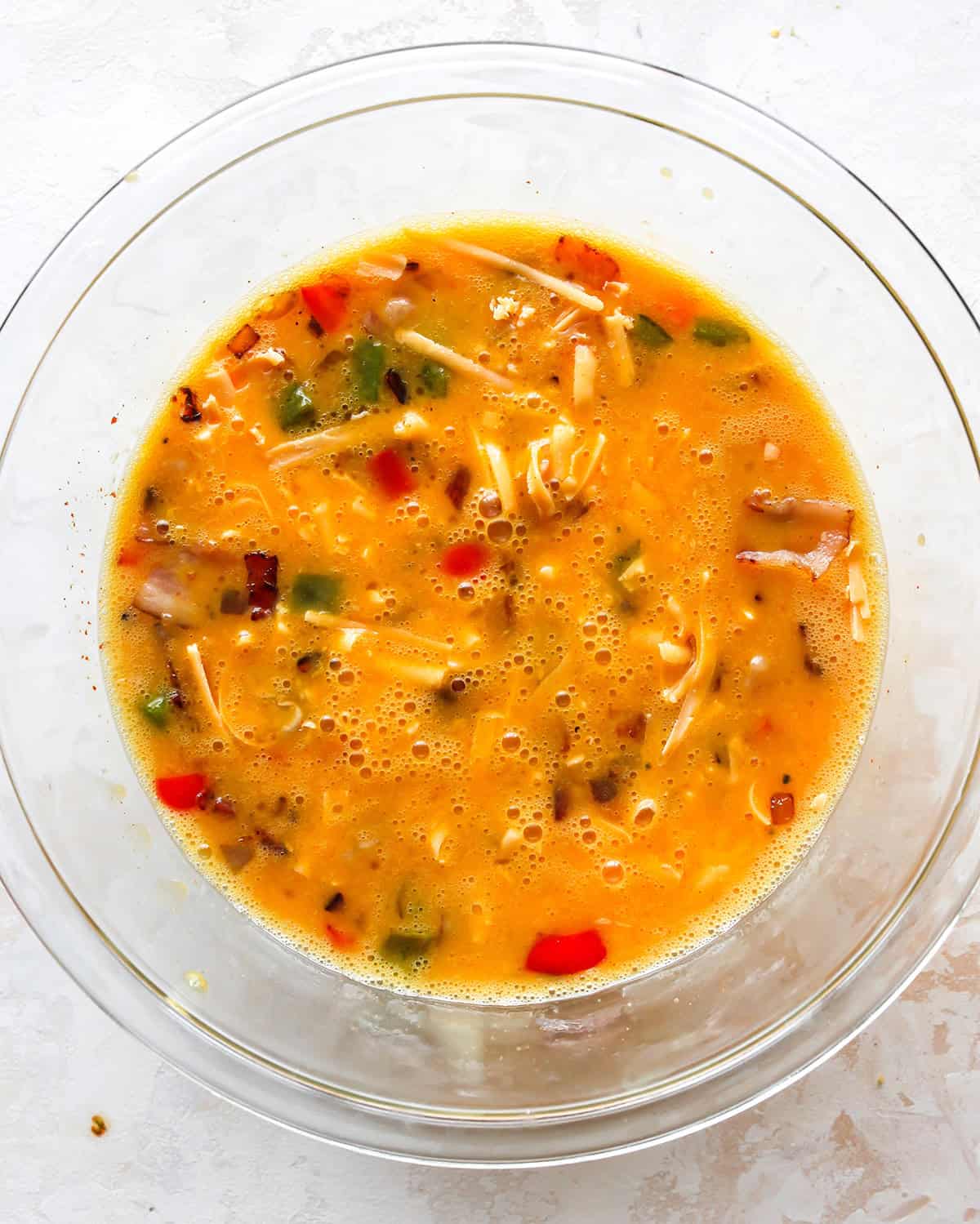 how to make egg bites - cheese added to the egg mixture in a glass bowl