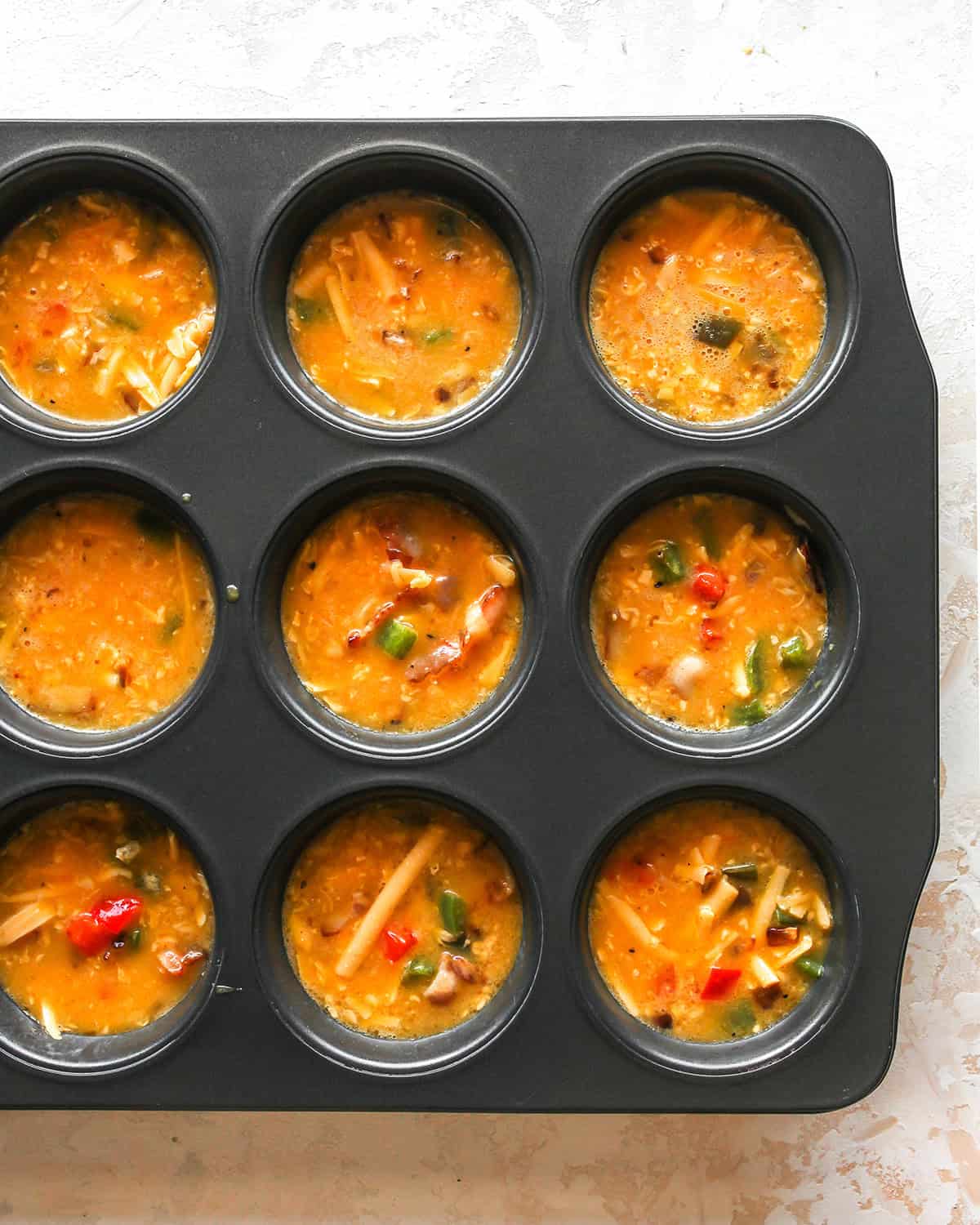 how to make egg bites - mixture in a muffin pan before baking