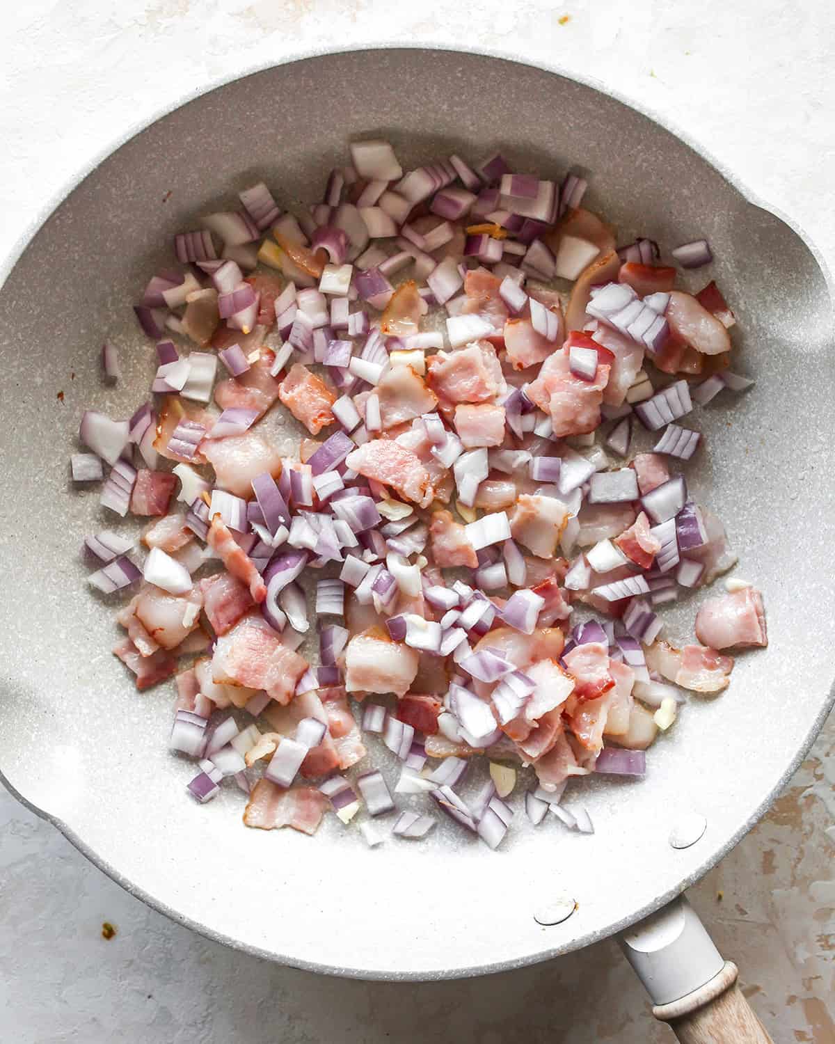 how to make egg bites - bacon, onion and garlic in a pan before cooking