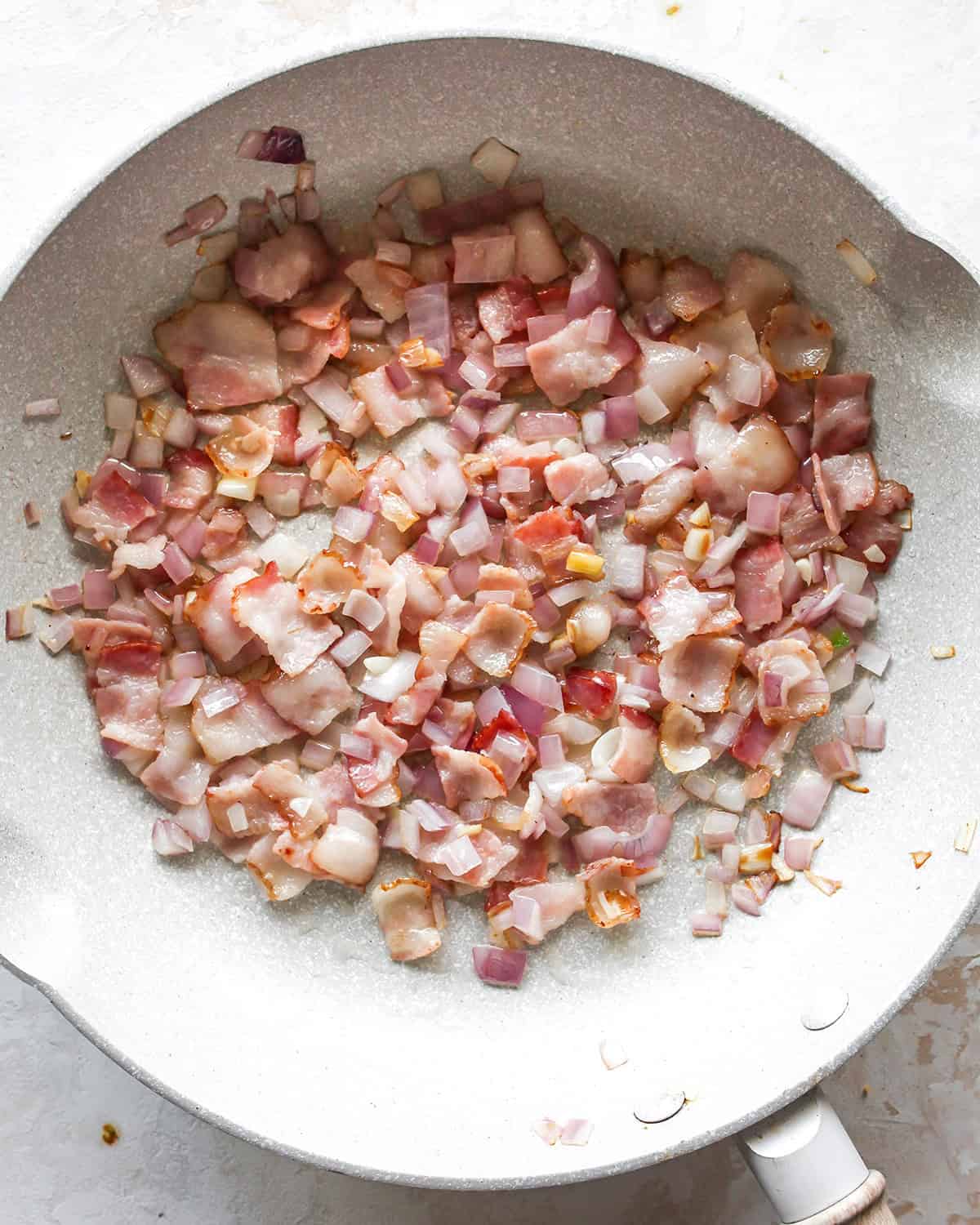 how to make egg bites - bacon onion and garlic in a pan after cooking