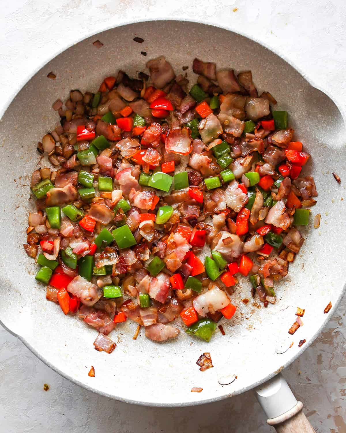 how to make egg bites - cooked bacon and veggies in a skillet cooling