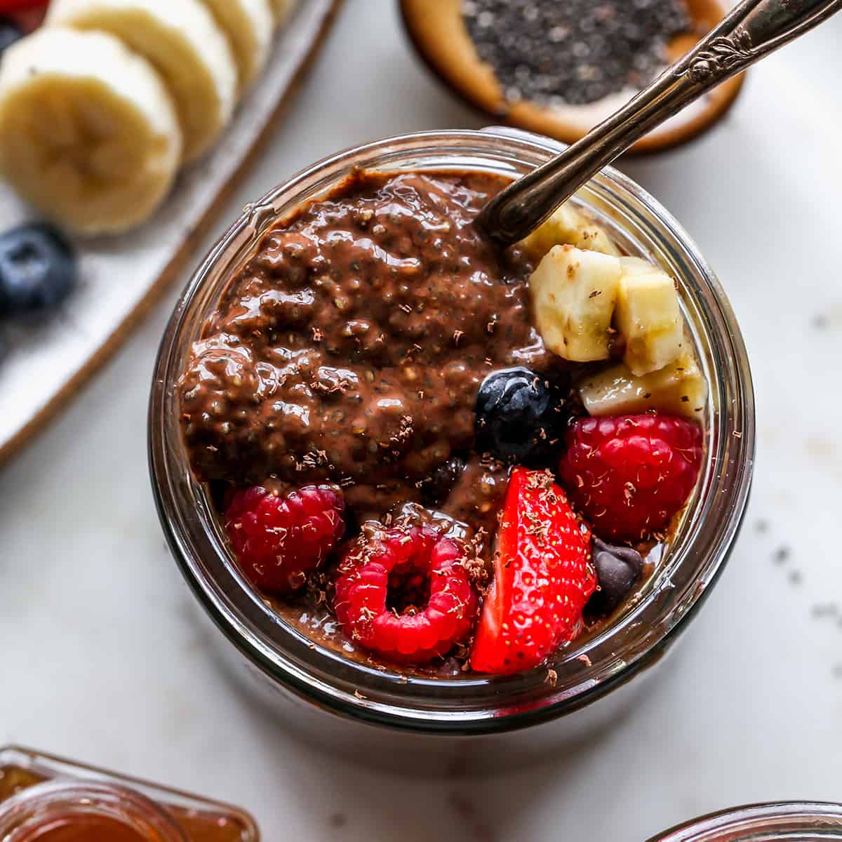 Chocolate Chia Seed Pudding in a jar with a spoon topped with fruit