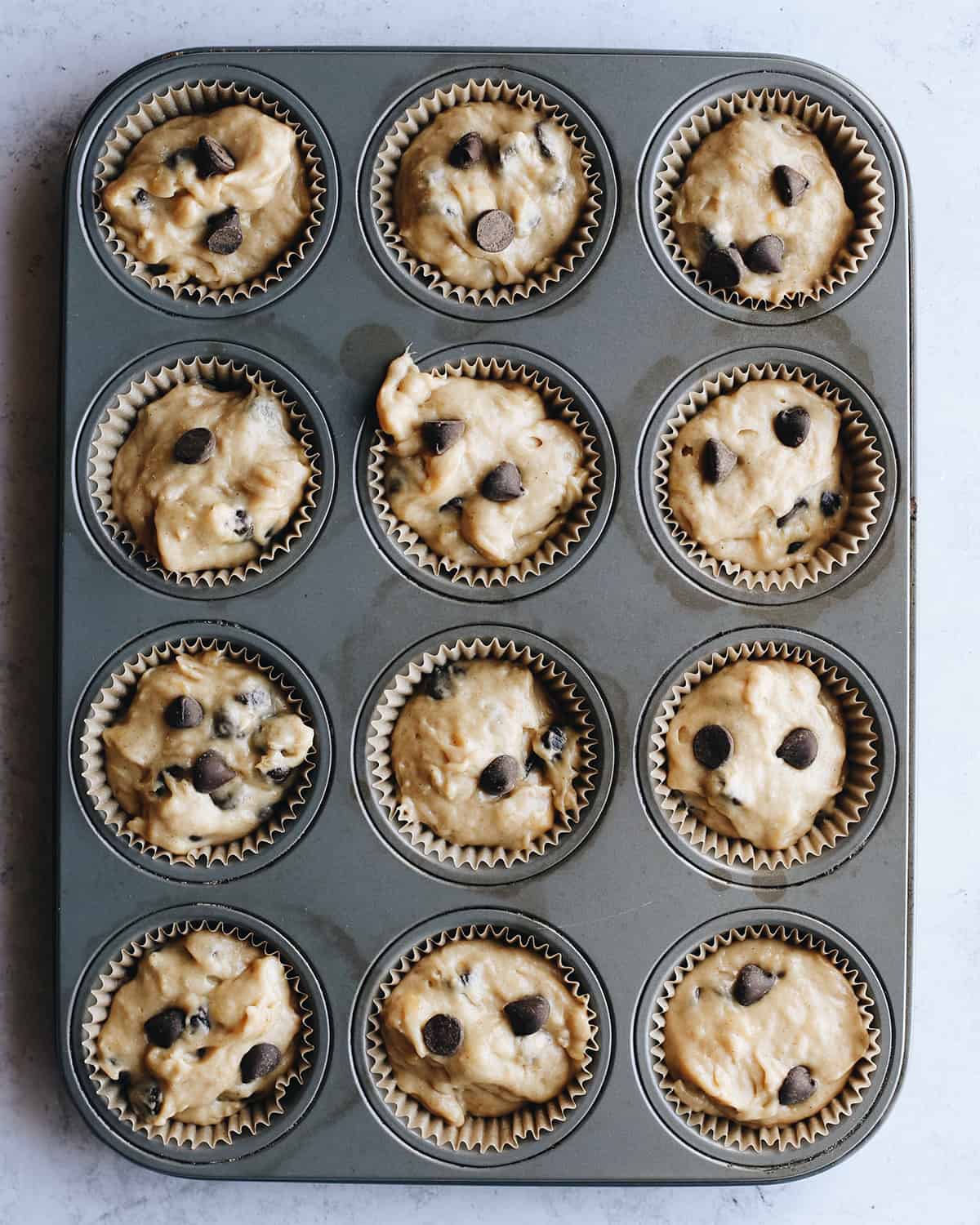 banana chocolate chip muffins in a muffin tin before baking