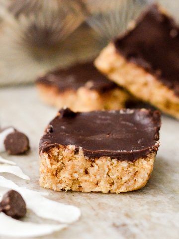 Finished No-Bake Coconut Almond Bars with chocolate chips next to them.