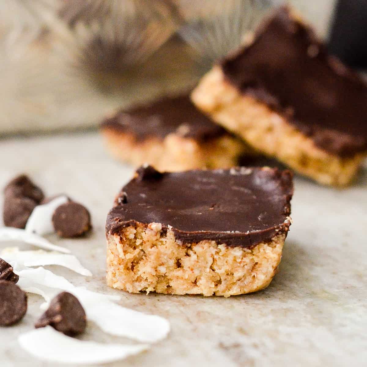 Finished Coconut Almond Bars with loose chocolate chips surrounding it. 