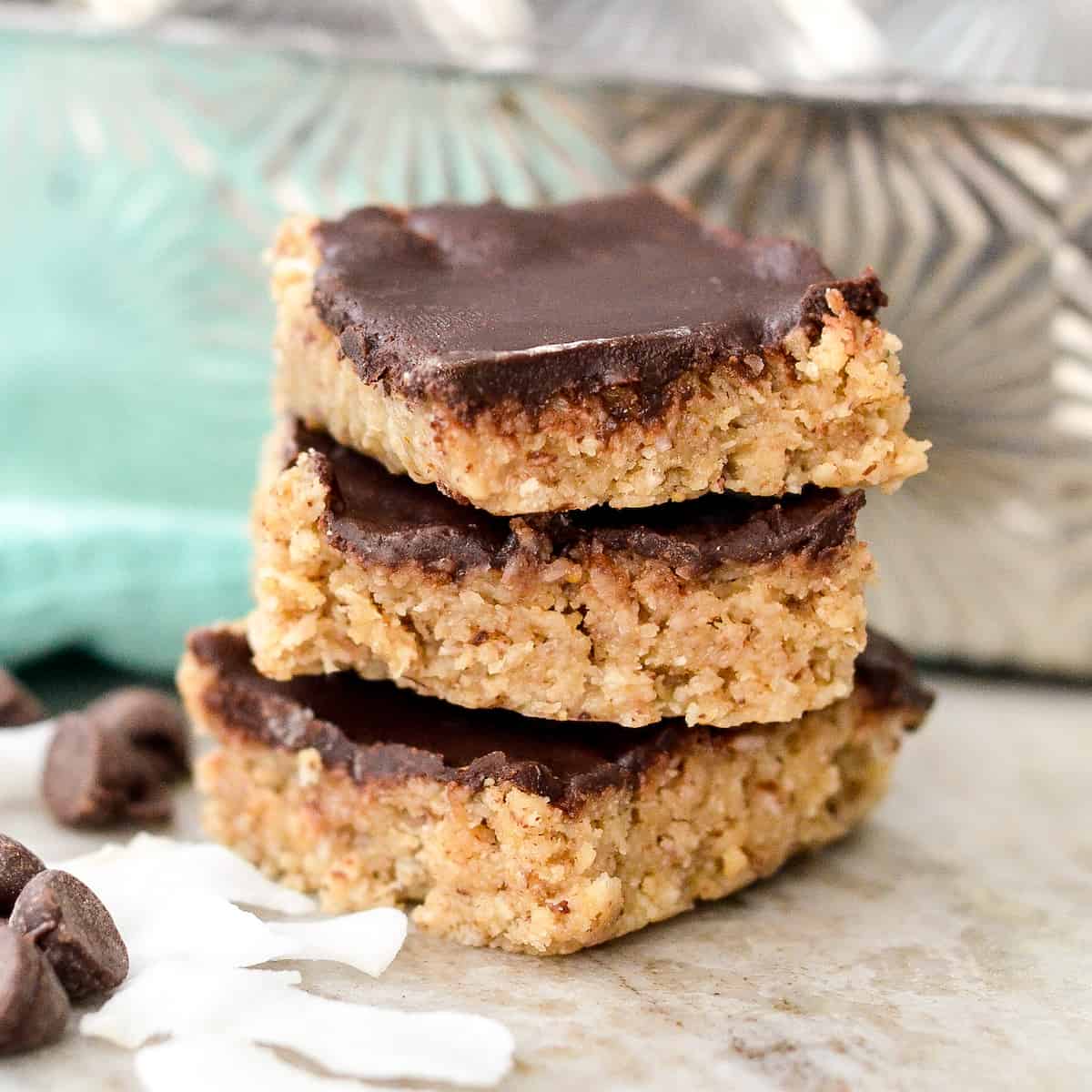 Three coconut-almond bars stacked with coconut shavings around it. 