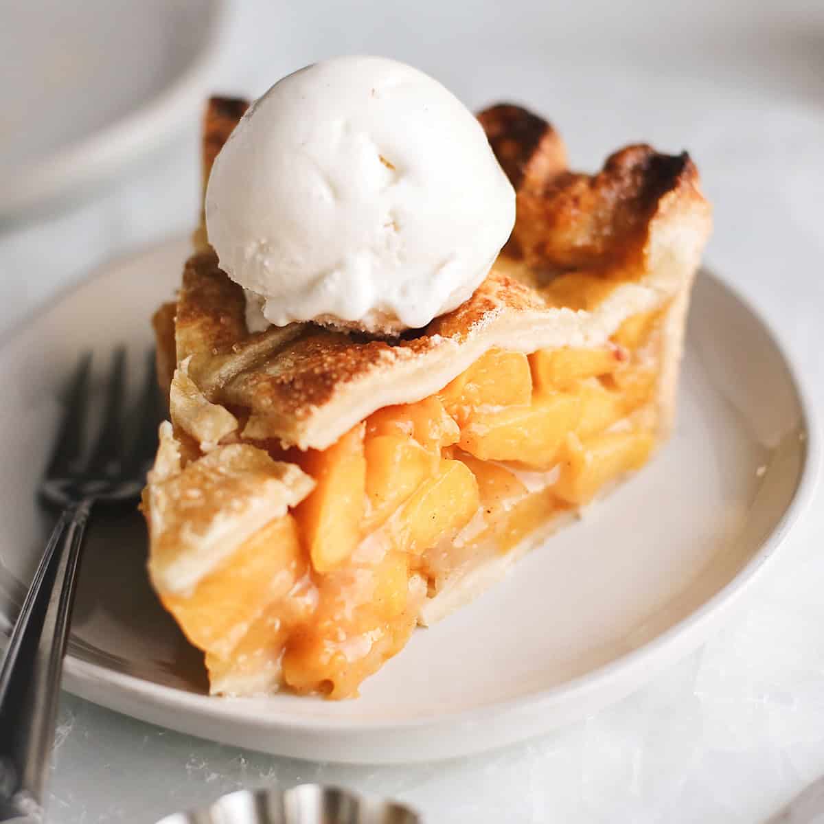 a slice of peach pie with vanilla ice cream on top