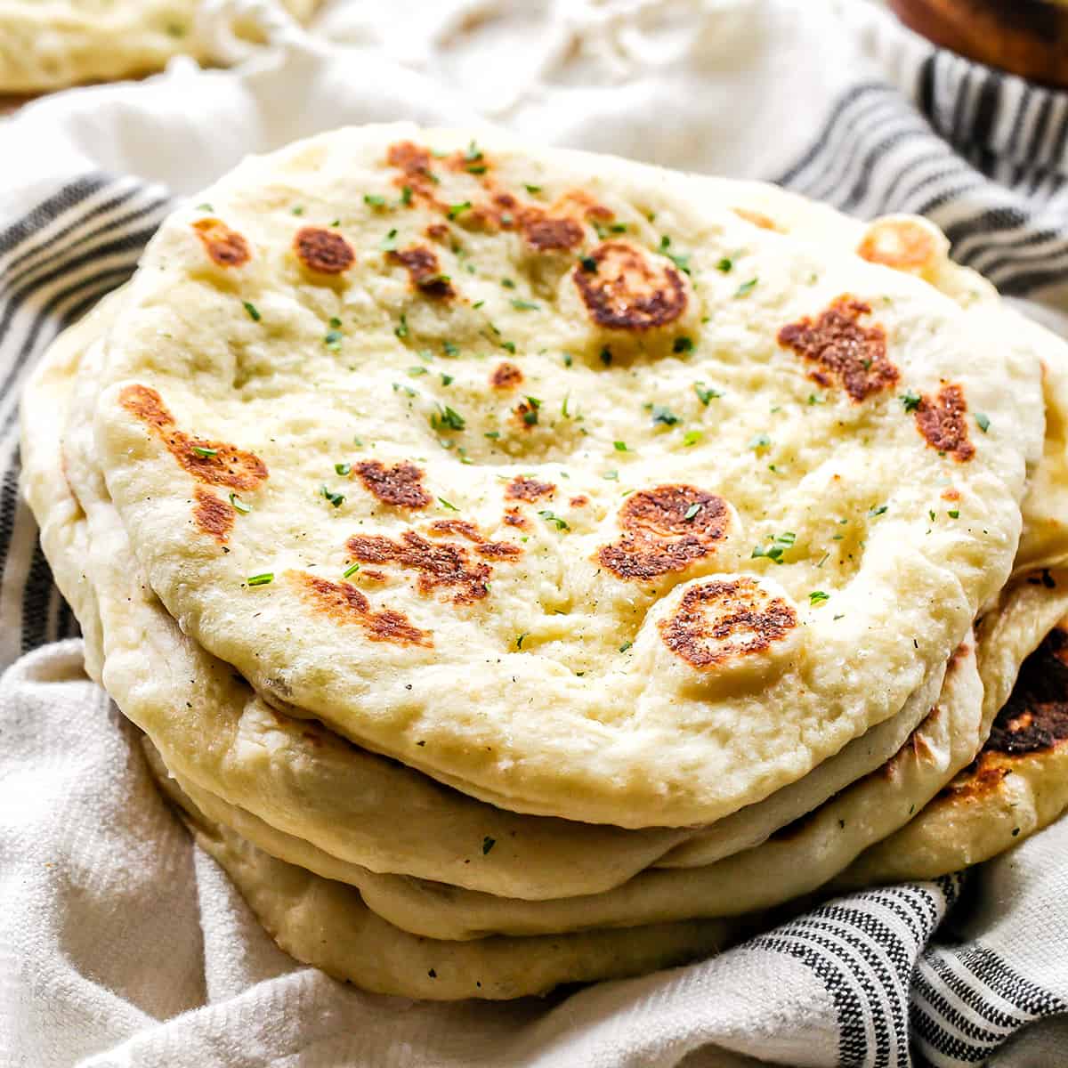 a stack of 4 pieces of Homemade Naan Bread Recipe topped with cilantro