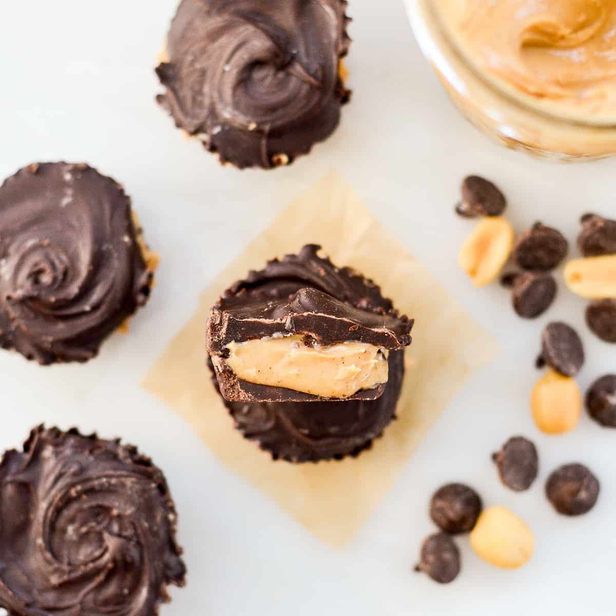 Overhead view of four Healthy Homemade Peanut Butter Cups, one cut in half with the inside showing. 