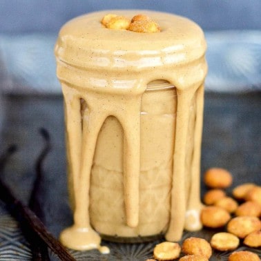 Front view of a jar of Homemade Honey Roasted Peanut Butter Recipe with some peanut butter dripping down the sides