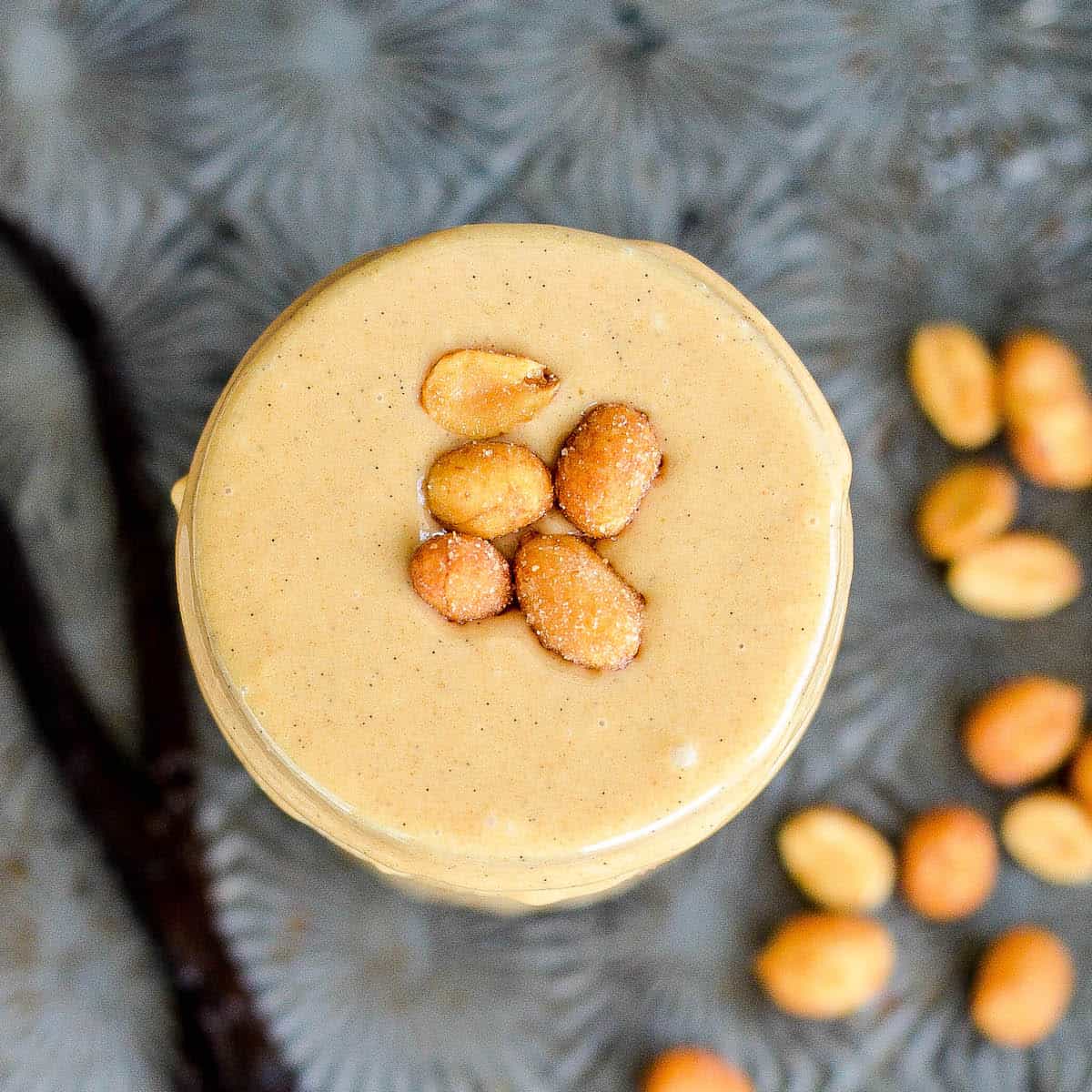 Overhead view of a jar of Peanut Butter topped with roasted peanuts.