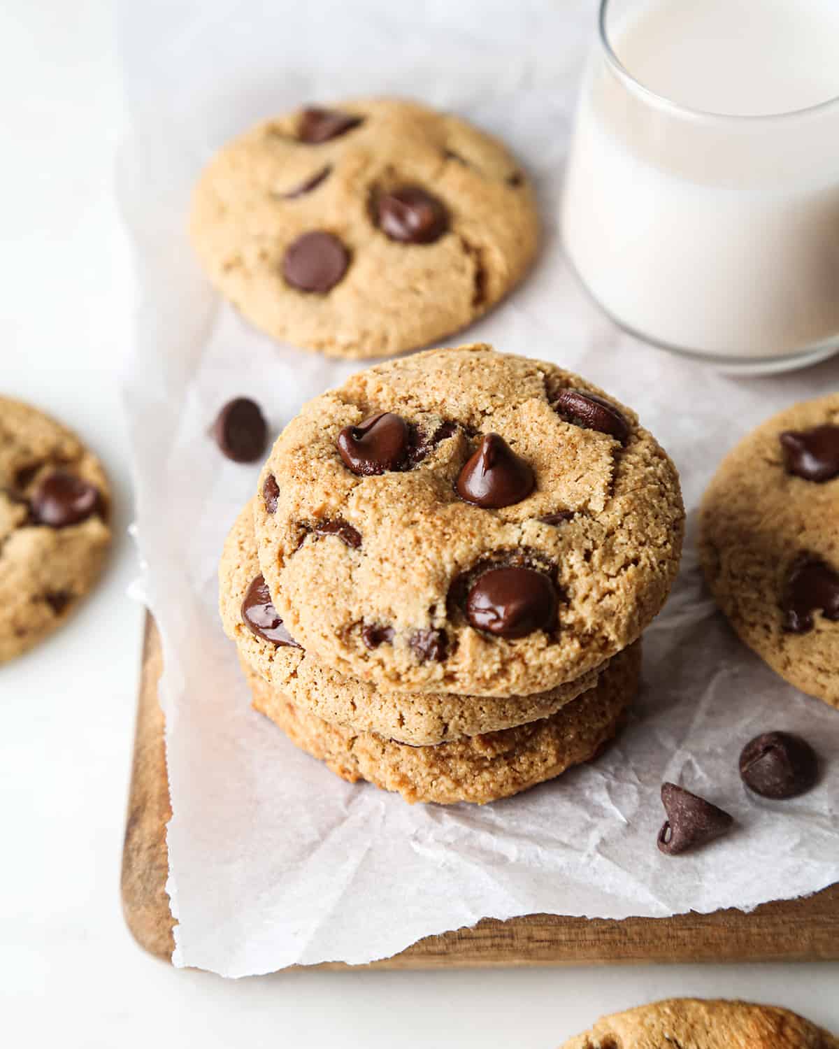 stack of 3 Paleo Chocolate Chip Cookies with other cookies around it and a glass of milk