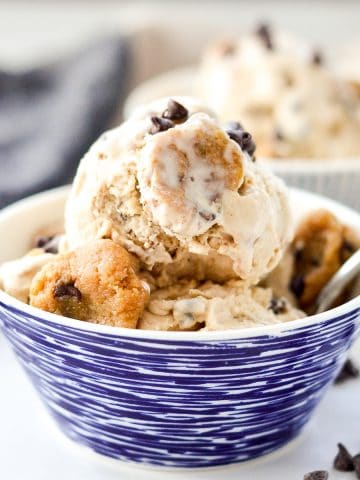 front view of a bowl of paleo cookie dough ice cream in a bowl with a spoon and chunks of cookie dough