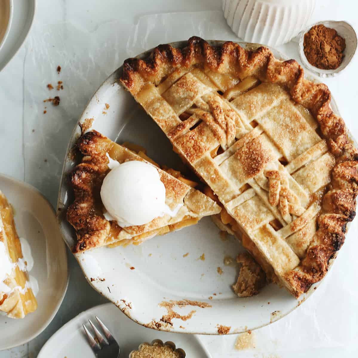 a peach pie with a slice cut out and ice cream on top of the slice. 