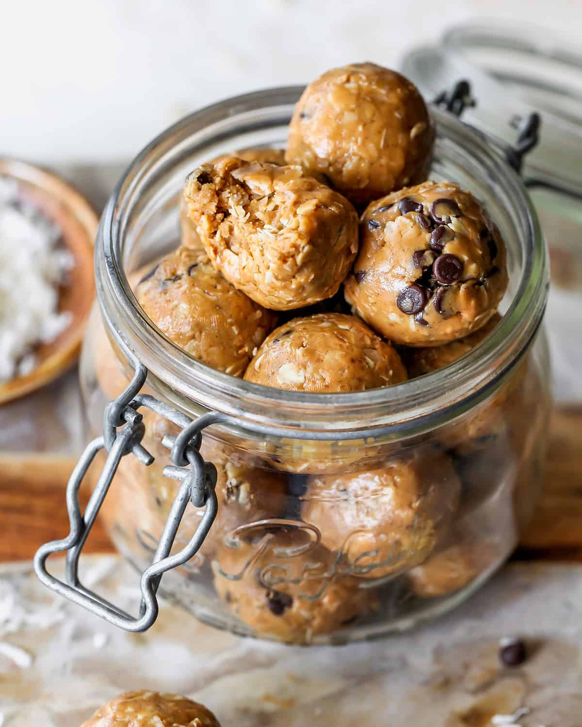 peanut butter energy balls in a glass jar, the top one has a bite taken out of it