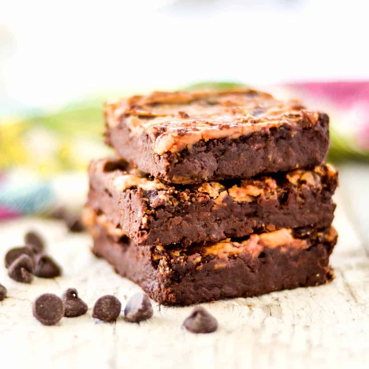 3 vegan brownies stacked with chocolate chips surround it. 