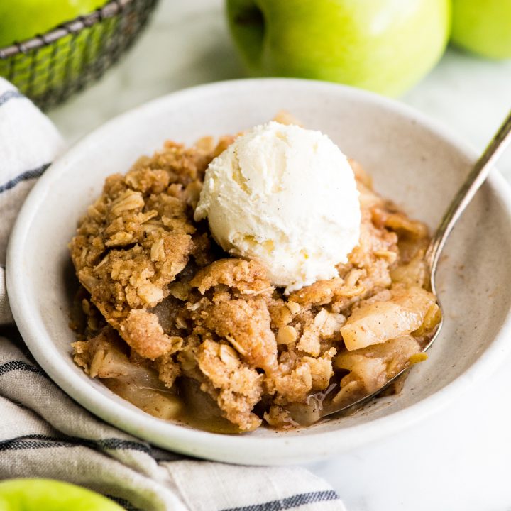 front view of a bowl of apple crisp with a scoop of ice cream on top 