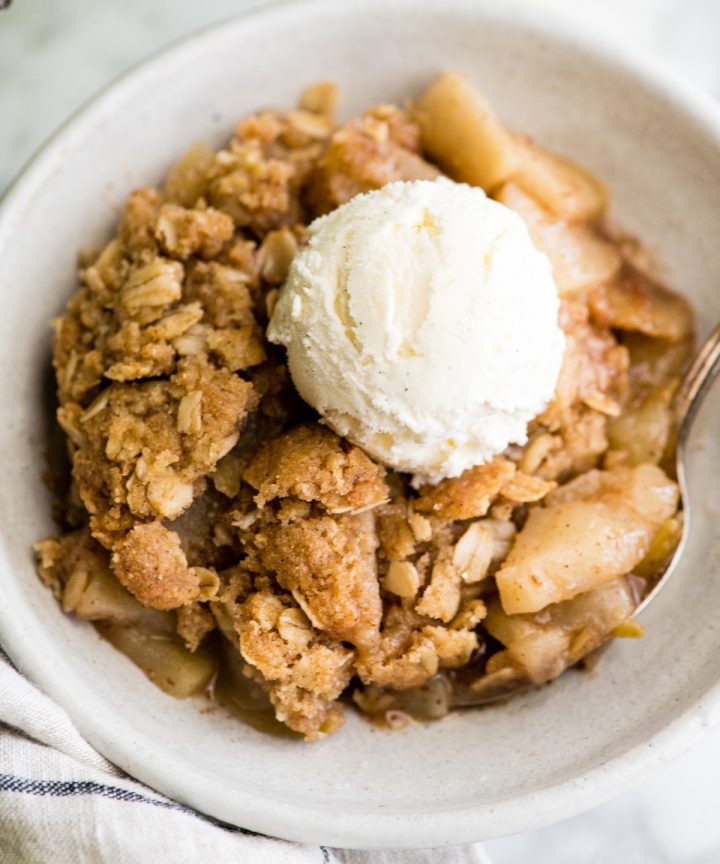 overhead view of apple crisp in a bowl with a scoop of ice cream on top