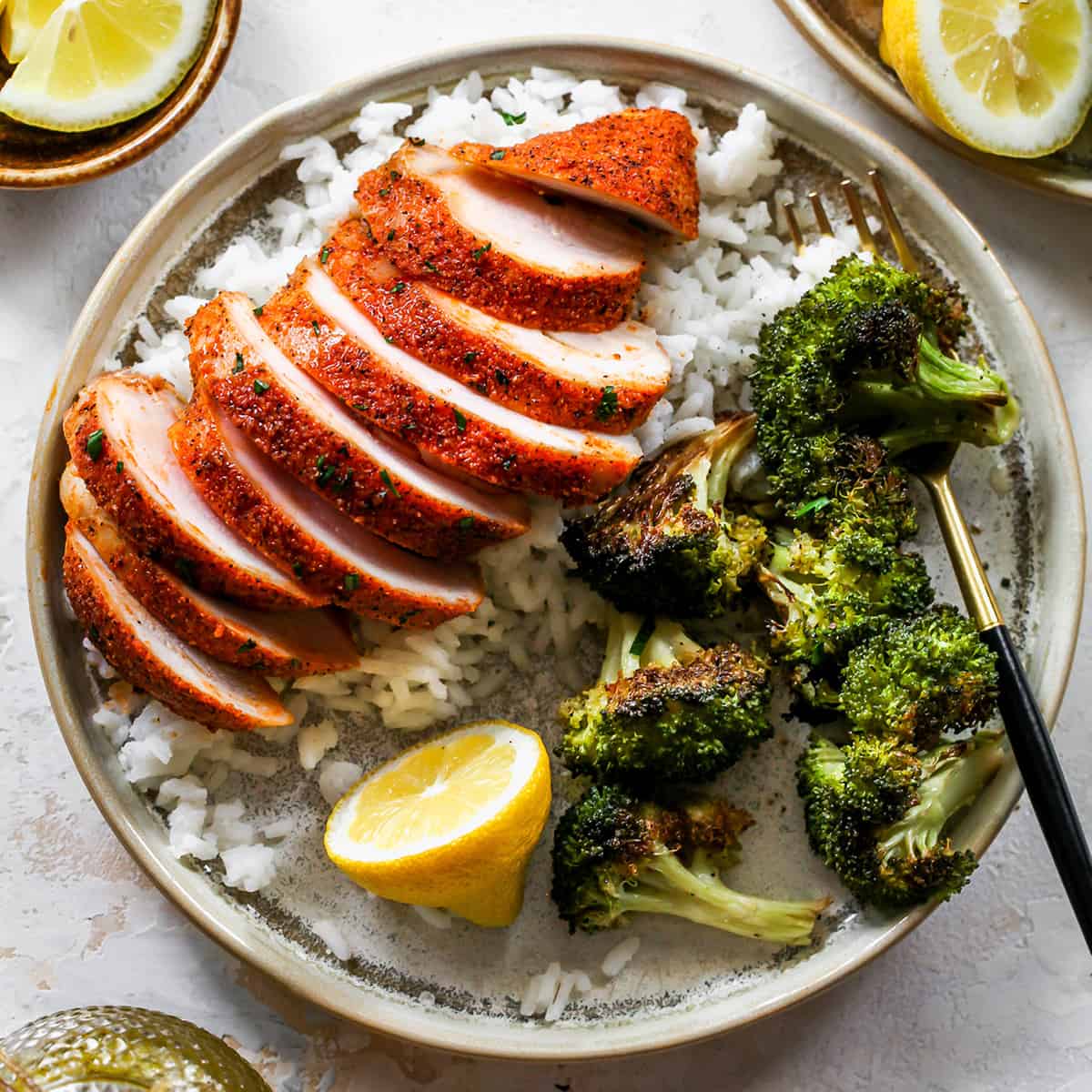 overhead view of a Baked Chicken Breast sliced on top of rice with a side of broccoli on a plate
