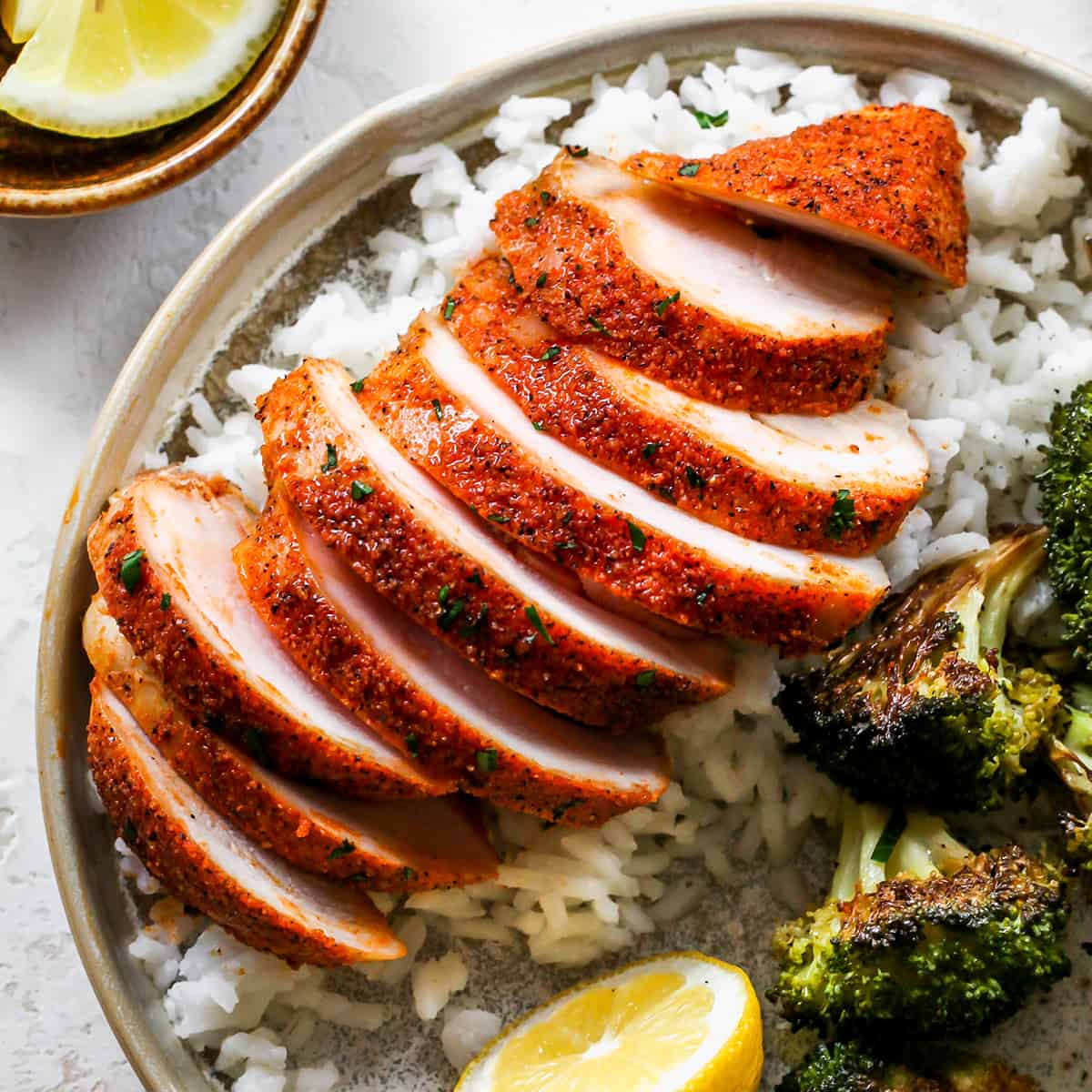 up close overhead view of a Baked Chicken Breast sliced on top of rice with a side of broccoli on a plate