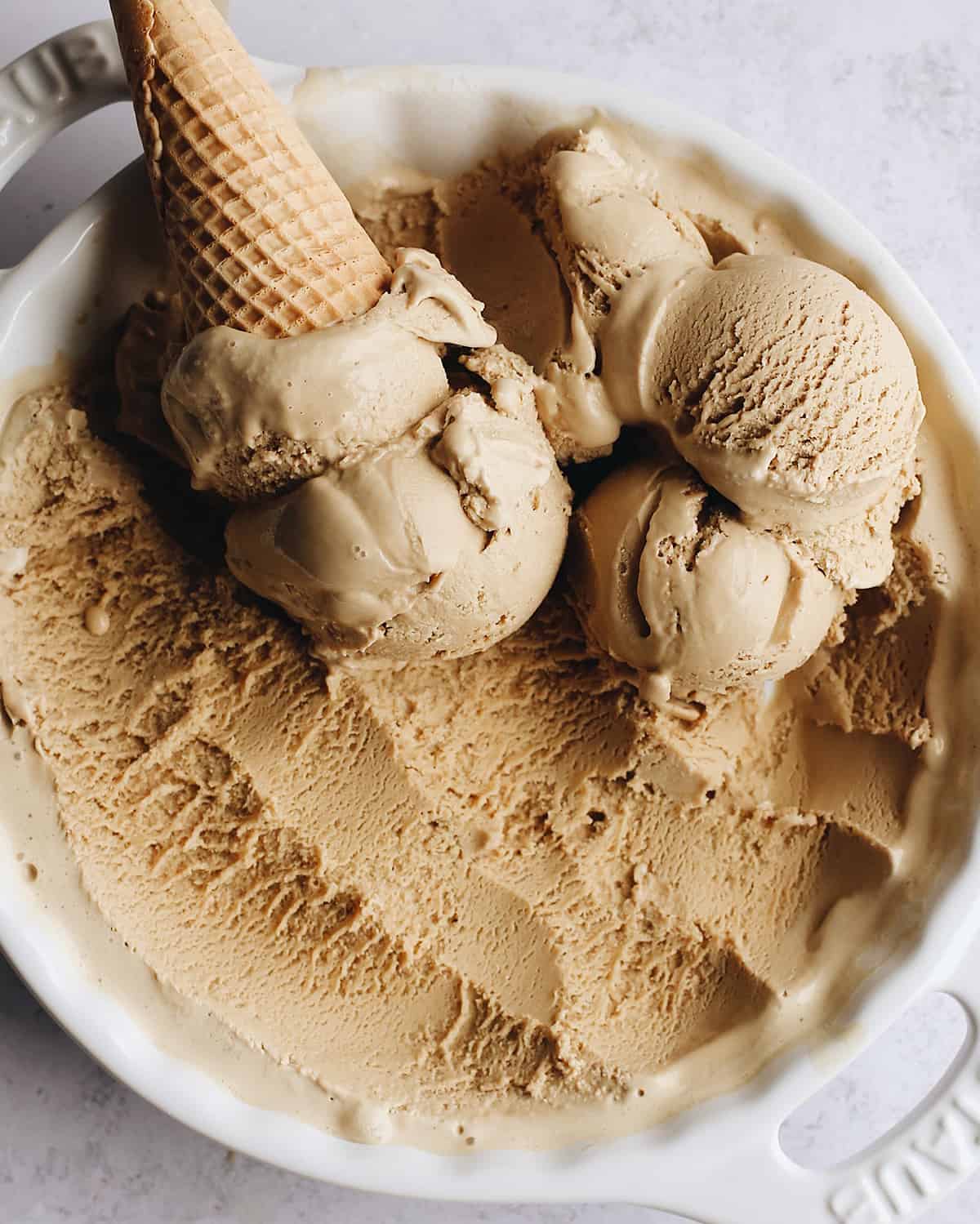overhead view of scoops of coffee ice cream in white container with an ice cream cone