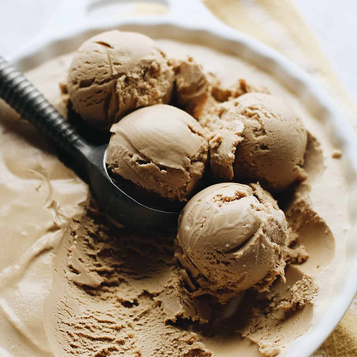 4 scoops of Coffee Ice Cream in a dish with an ice cream scoop