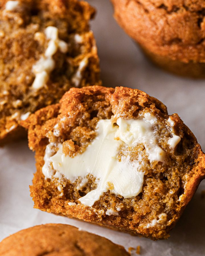 half of a pumpkin muffin with butter on it. 