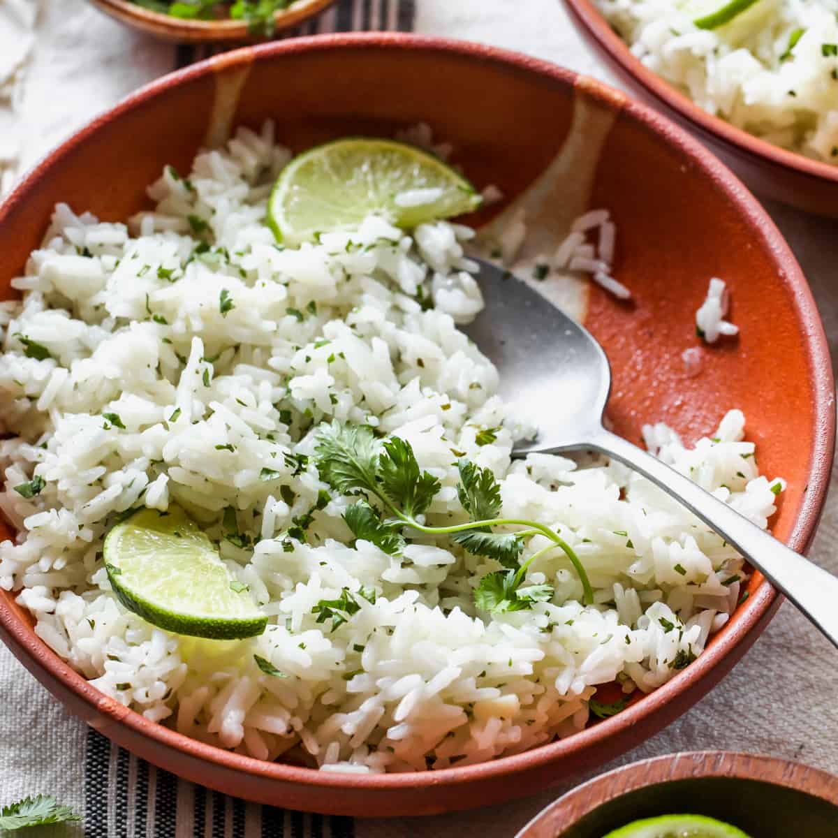 front view of a bowl of Cilantro Lime Rice garnished with cilantro and limes