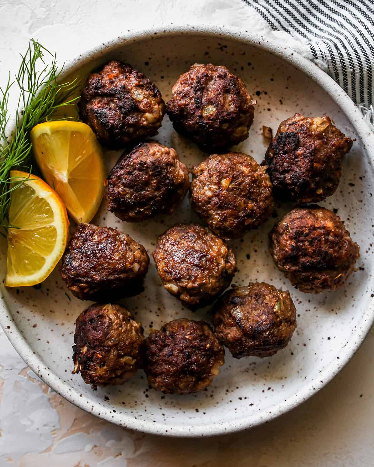 11 Greek Meatballs on a plate with lemon and fresh dill