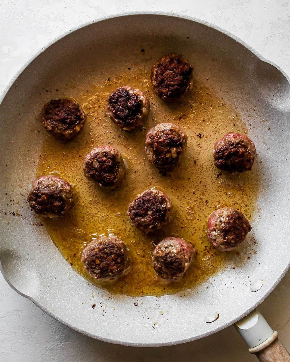 Greek Meatballs cooking on the second side in a frying pan